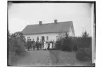 Envånings bostadshus, 17 personer framför huset.
L.E. Larsson