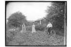 Envånings bostadshus och uthus, två kvinnor och en man med cykel.
Petrus Johansson