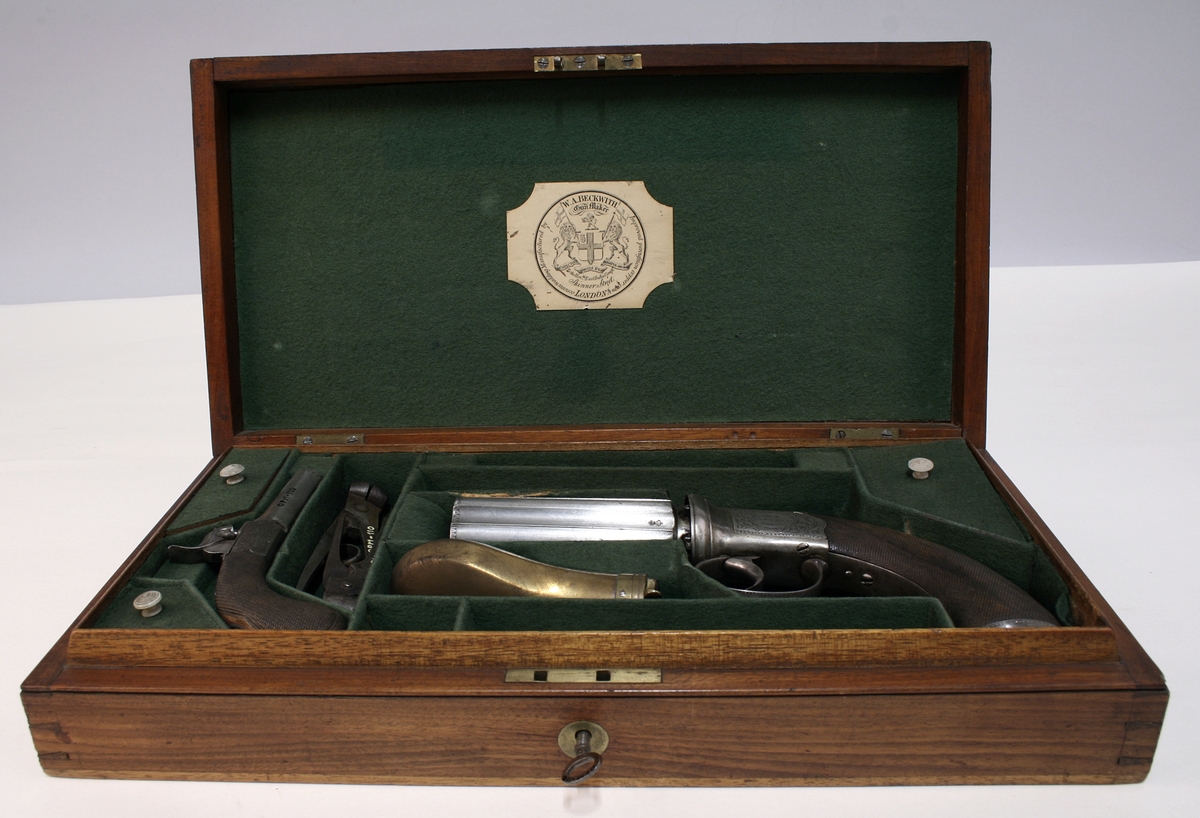 Revolver i "cased set", bestående av revolver (Pepperbox), en enkeltløpet perkusjonspistol samt diverse verktøy, alt liggende i mahognykasse. Bestandelene er følgende: 

KASSE av mahogny, 36,6 x 18,6 x 6,6, cm og er forsynt med lokk som har to mesinghengsler i bakkant. På forsiden er det lås med medding nøkkelhullbeslag på forsiden. Nøkkel av jern, ca. 2,9 cm lang. Midt på lokket er det et rundt messingskilt med profilert kant. Skiltets diameter er 3,8 cm. Kassen er indelt i 11 rom hvorav tre er forsynt med lokk med små, hvite gripehåndtak, runde, knappformede med diameter 1,05 cm. Alle rom er trukket med grønn filt. På lokkets innside er klebet produssentens merkelapp.

REVOLVER. Såkalt "Pepperboks". Et revolverende kammerstykke hvor hver kammer utgjør en selvstendig pipe, en forløper for de senere revolveremed kort tønne og langt løp. Kammerstykket (tønne) er 10 cm langt, hver løp har et kaliber på litt underkant av 10 mm. I bakkant er pipene forsaynt med pistong. På utsiden er pipene ca, 1,2 cm fra pistongene, merket fortløpende med nummer 1 - 6 . Mellom pipene er kammerstykket merket vekselsvis med kronet CP og V. Revolveren har overliggendeslaghane med gravert blomsterranke motiver. Bakenfor hanen er det en bevegelig sikringsfløy. Sideblikkene er prydet med graverte blomsterranker,det venstre sideblikket er markert "W.A. BECHWITH LONDON". Avtrekksbøylen er prydet med blomsterranke motiver. Grepsplater av mørkebrunt tre som er filt i rombemønster. Kolbekappen et oval og svakt buet , er kantet med en smal bord og har i midten et gravert, rundt lokk innenfor hvilket er et lite rom for kuler og fenghetter. Grepet har et lite firkantetntommeskilt med brutte hjørner. Alle beslag er av stål. 

PISTOL. Enkeltløpet, total lengde 13,2 cm. Pipen har et kaliber som revolveren. Pipen er 5,4 cm lang og er stemplet med kronet CP og V. Slaghanene står midt oppå pistolen, stikkende opp mellom sideblikkene. Hanen har skjellmønstret dekor og er forsynt med et par øyne. Når hanen spennes, felles en avtrekker fram under under pistolen. Sideblikkene er dekorert med blomsterranker. Den høyre sideblikket er merket "LONDON" og det venstre "H.BECHWIT ", Grepet er av tre,mørkebrunt og er filt i rombemønster. På grepet sitter et ovalt tommeskilt. 
KRUTTFLASKE. Av messing, 11,4 cm lang, flaskeformet, noe flattrykt mot den nedre delen hvor  det vider seg ut i bredden. Festeskrue og fjær for lukkemekanisme er av stål. 
LADE7PUSSESTOKK. av gulfarget med  et 4,6 cm riflet mesinghode. Total lengde 17,6 cm. Vekt.: 14g. 
KULETANG. Av jern, 8,6 cm lang, merket "1". Vekt: 45 g. 
KULETANF. Av jern, 11,5 cm lang, merket "82". Vekt: 44 g. 
PISTOLNØKKEL. For fjerning og innsetting av pistonger på revolveren. 11,3 cm langt og med sortlakkert treskaft. Vekt. 17 g.