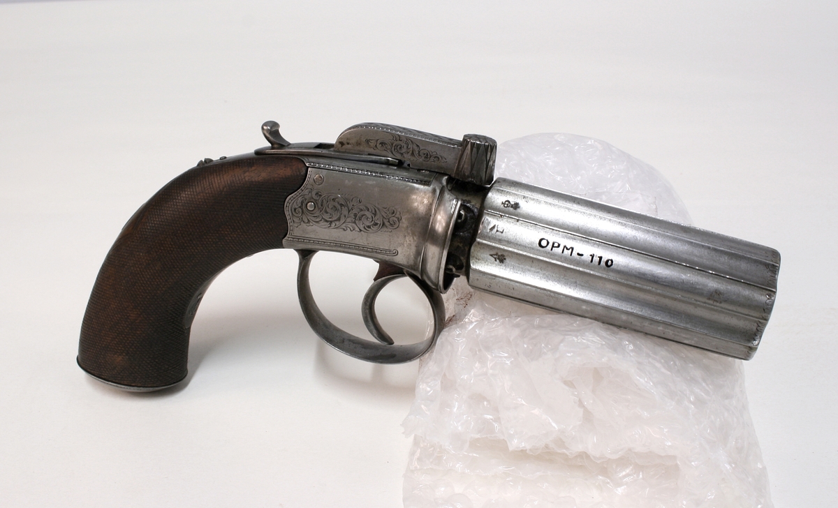 Revolver i "cased set", bestående av revolver (Pepperbox), en enkeltløpet perkusjonspistol samt diverse verktøy, alt liggende i mahognykasse. Bestandelene er følgende: 

KASSE av mahogny, 36,6 x 18,6 x 6,6, cm og er forsynt med lokk som har to mesinghengsler i bakkant. På forsiden er det lås med medding nøkkelhullbeslag på forsiden. Nøkkel av jern, ca. 2,9 cm lang. Midt på lokket er det et rundt messingskilt med profilert kant. Skiltets diameter er 3,8 cm. Kassen er indelt i 11 rom hvorav tre er forsynt med lokk med små, hvite gripehåndtak, runde, knappformede med diameter 1,05 cm. Alle rom er trukket med grønn filt. På lokkets innside er klebet produssentens merkelapp.

REVOLVER. Såkalt "Pepperboks". Et revolverende kammerstykke hvor hver kammer utgjør en selvstendig pipe, en forløper for de senere revolveremed kort tønne og langt løp. Kammerstykket (tønne) er 10 cm langt, hver løp har et kaliber på litt underkant av 10 mm. I bakkant er pipene forsaynt med pistong. På utsiden er pipene ca, 1,2 cm fra pistongene, merket fortløpende med nummer 1 - 6 . Mellom pipene er kammerstykket merket vekselsvis med kronet CP og V. Revolveren har overliggendeslaghane med gravert blomsterranke motiver. Bakenfor hanen er det en bevegelig sikringsfløy. Sideblikkene er prydet med graverte blomsterranker,det venstre sideblikket er markert "W.A. BECHWITH LONDON". Avtrekksbøylen er prydet med blomsterranke motiver. Grepsplater av mørkebrunt tre som er filt i rombemønster. Kolbekappen et oval og svakt buet , er kantet med en smal bord og har i midten et gravert, rundt lokk innenfor hvilket er et lite rom for kuler og fenghetter. Grepet har et lite firkantetntommeskilt med brutte hjørner. Alle beslag er av stål. 

PISTOL. Enkeltløpet, total lengde 13,2 cm. Pipen har et kaliber som revolveren. Pipen er 5,4 cm lang og er stemplet med kronet CP og V. Slaghanene står midt oppå pistolen, stikkende opp mellom sideblikkene. Hanen har skjellmønstret dekor og er forsynt med et par øyne. Når hanen spennes, felles en avtrekker fram under under pistolen. Sideblikkene er dekorert med blomsterranker. Den høyre sideblikket er merket "LONDON" og det venstre "H.BECHWIT ", Grepet er av tre,mørkebrunt og er filt i rombemønster. På grepet sitter et ovalt tommeskilt. 
KRUTTFLASKE. Av messing, 11,4 cm lang, flaskeformet, noe flattrykt mot den nedre delen hvor  det vider seg ut i bredden. Festeskrue og fjær for lukkemekanisme er av stål. 
LADE7PUSSESTOKK. av gulfarget med  et 4,6 cm riflet mesinghode. Total lengde 17,6 cm. Vekt.: 14g. 
KULETANG. Av jern, 8,6 cm lang, merket "1". Vekt: 45 g. 
KULETANF. Av jern, 11,5 cm lang, merket "82". Vekt: 44 g. 
PISTOLNØKKEL. For fjerning og innsetting av pistonger på revolveren. 11,3 cm langt og med sortlakkert treskaft. Vekt. 17 g.