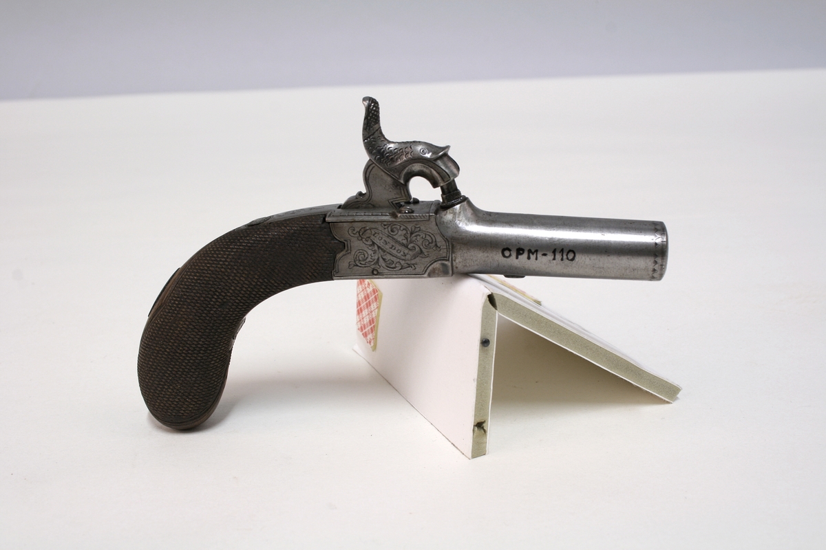 Revolver i "cased set", bestående av revolver (Pepperbox), en enkeltløpet perkusjonspistol samt diverse verktøy, alt liggende i mahognykasse. Bestandelene er følgende: 

KASSE av mahogny, 36,6 x 18,6 x 6,6, cm og er forsynt med lokk som har to mesinghengsler i bakkant. På forsiden er det lås med medding nøkkelhullbeslag på forsiden. Nøkkel av jern, ca. 2,9 cm lang. Midt på lokket er det et rundt messingskilt med profilert kant. Skiltets diameter er 3,8 cm. Kassen er indelt i 11 rom hvorav tre er forsynt med lokk med små, hvite gripehåndtak, runde, knappformede med diameter 1,05 cm. Alle rom er trukket med grønn filt. På lokkets innside er klebet produssentens merkelapp.

REVOLVER. Såkalt "Pepperboks". Et revolverende kammerstykke hvor hver kammer utgjør en selvstendig pipe, en forløper for de senere revolveremed kort tønne og langt løp. Kammerstykket (tønne) er 10 cm langt, hver løp har et kaliber på litt underkant av 10 mm. I bakkant er pipene forsaynt med pistong. På utsiden er pipene ca, 1,2 cm fra pistongene, merket fortløpende med nummer 1 - 6 . Mellom pipene er kammerstykket merket vekselsvis med kronet CP og V. Revolveren har overliggendeslaghane med gravert blomsterranke motiver. Bakenfor hanen er det en bevegelig sikringsfløy. Sideblikkene er prydet med graverte blomsterranker,det venstre sideblikket er markert "W.A. BECHWITH LONDON". Avtrekksbøylen er prydet med blomsterranke motiver. Grepsplater av mørkebrunt tre som er filt i rombemønster. Kolbekappen et oval og svakt buet , er kantet med en smal bord og har i midten et gravert, rundt lokk innenfor hvilket er et lite rom for kuler og fenghetter. Grepet har et lite firkantetntommeskilt med brutte hjørner. Alle beslag er av stål. 

PISTOL. Enkeltløpet, total lengde 13,2 cm. Pipen har et kaliber som revolveren. Pipen er 5,4 cm lang og er stemplet med kronet CP og V. Slaghanene står midt oppå pistolen, stikkende opp mellom sideblikkene. Hanen har skjellmønstret dekor og er forsynt med et par øyne. Når hanen spennes, felles en avtrekker fram under under pistolen. Sideblikkene er dekorert med blomsterranker. Den høyre sideblikket er merket "LONDON" og det venstre "H.BECHWIT ", Grepet er av tre,mørkebrunt og er filt i rombemønster. På grepet sitter et ovalt tommeskilt. 
KRUTTFLASKE. Av messing, 11,4 cm lang, flaskeformet, noe flattrykt mot den nedre delen hvor  det vider seg ut i bredden. Festeskrue og fjær for lukkemekanisme er av stål. 
LADE7PUSSESTOKK. av gulfarget med  et 4,6 cm riflet mesinghode. Total lengde 17,6 cm. Vekt.: 14g. 
KULETANG. Av jern, 8,6 cm lang, merket "1". Vekt: 45 g. 
KULETANF. Av jern, 11,5 cm lang, merket "82". Vekt: 44 g. 
PISTOLNØKKEL. For fjerning og innsetting av pistonger på revolveren. 11,3 cm langt og med sortlakkert treskaft. Vekt. 17 g.
