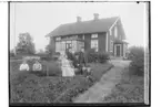 En och en halvvånings bostadshus med förstuga och glasad veranda. Sju personer framför huset.
Elof Johansson