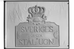 Örebro Läns Museum, Slottet.
Hugo Hedberg.
Järnskylt med följande text: 'Sveriges Första Stål-ugn'.