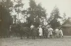 En hästdragen kokvagn uppställd för fotografering. Framför vagnen står soldater. En del av soldaterna håller soppsked, yxa och såg i sina händer.