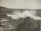 Naturbild på havet med kraftiga vågor som slår mot strandklippor.