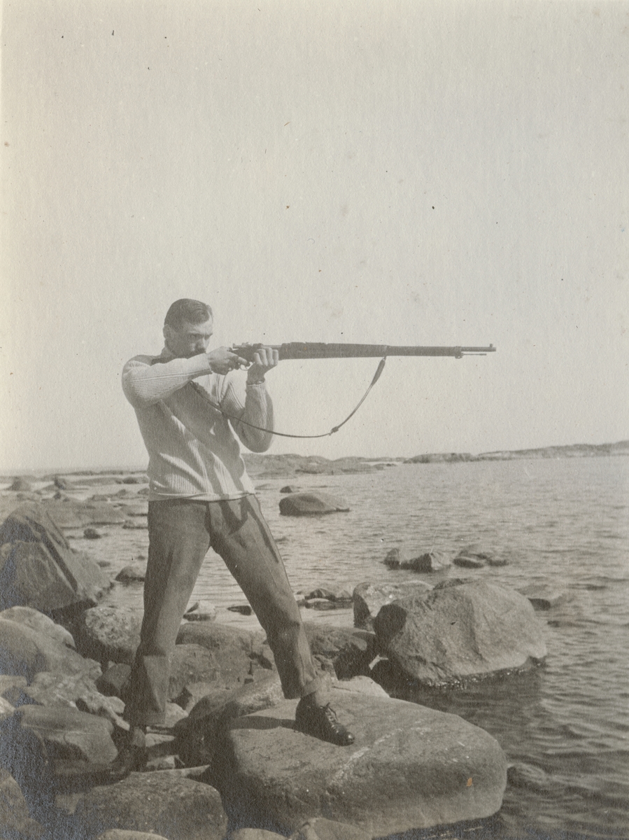 Soldat siktar med gevär på stranden.