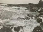 Naturbild på havet med vågor som slår mot strandklippor.