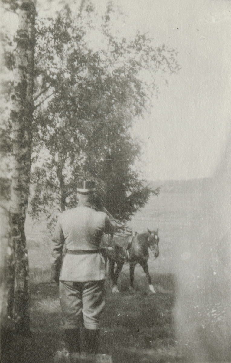 En officerare hälsar på sin häst i trädgården.