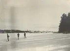 Soldater åker skidor på sjön. I bakgrunden syns bebyggelse vid Strömsund.