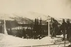 Landsgräns mellan Sverige och Norge. Tre soldater på skidor vid en gränsskylt. Rågången fortsätter genom dalen till berget på motsatta sidan.