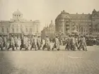 Soldater från officerskursen 1916-1917 på Militärhögskolan Karlberg marscherar mot Nybrokajen. I bakrunden syns Kungliga dramtiska teatern - Dramaten.