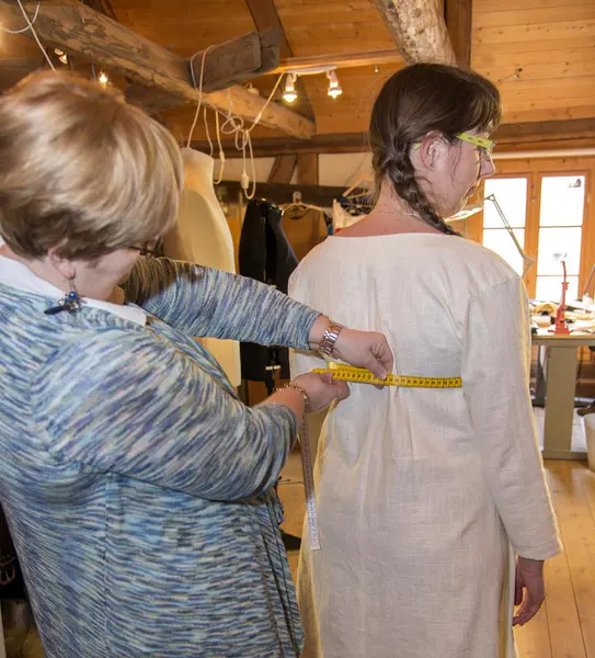 Skredderen måler modellen med et målebånd rundt livet.