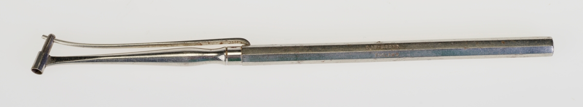 Amalgamstopper i metall med åttekantet håndtak. Instrumentet har en liten tube ytterst. En fjær forbundet med en "plunger" presser amalgamet ut av tuben og inn i hullet som skal fylles.