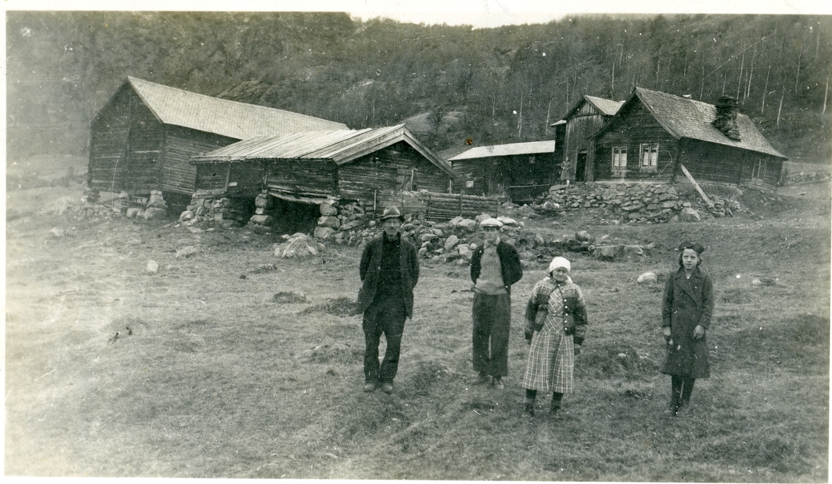 Ei ungjente, ei kvinne og to menn står nedenfor Sørre Hemsing gard, Vang i Valdres