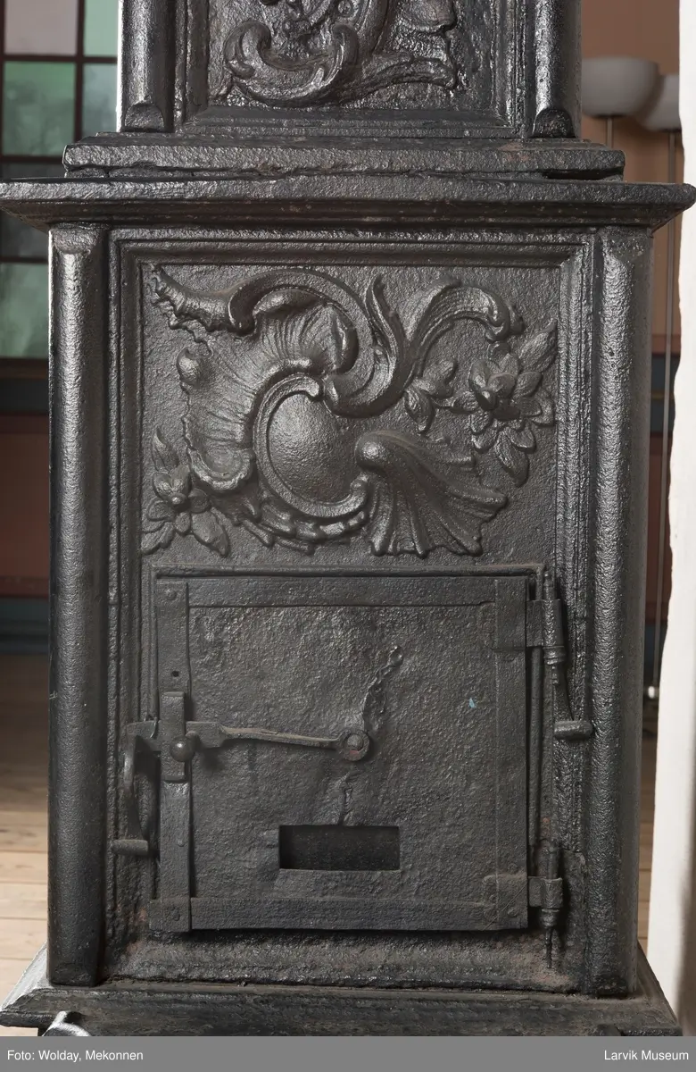 Ovn i  2 etasjer. 
Rokokko, jfr. nr 411 i Norsk Jernskulptur b II 
1. etasje langside: Mars sitter på en kanon med sverd i høyre hånd. Riflet bunn.
1 etasje kortside: Øverst: Rokokko-ornament, nederst: Grevekrone monogram. FL og 1756 
nederst: ovnsdør 2 hengsler ovalt askebrett med profilert kant.
2.etasje langside: Fyldig rokokko-ornament. med blomster. Uregelemessig portalåpning. 
2. etasje kortside: Rokokko-ornament, 
Ovnen har sungne ben m/dyreføtter