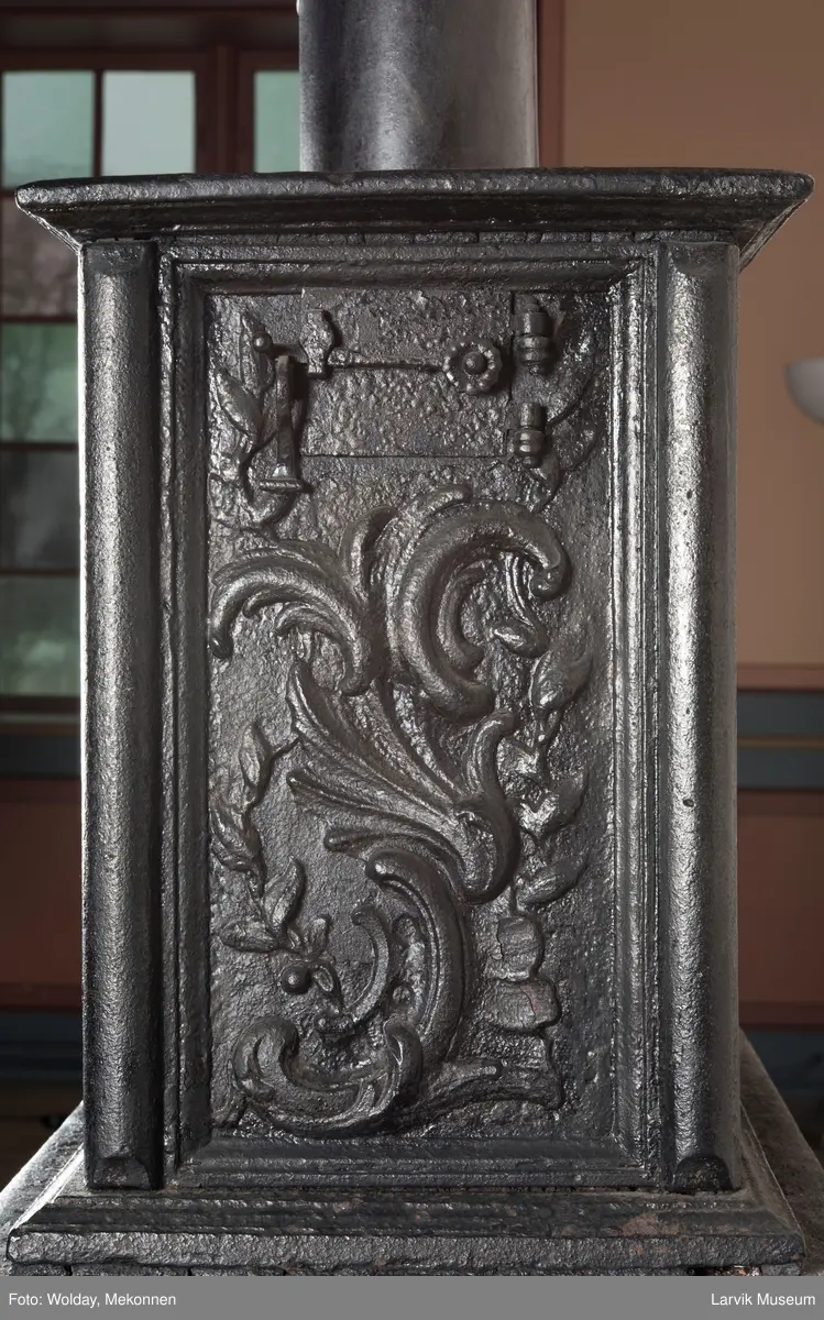 Ovn i  2 etasjer. 
Rokokko, jfr. nr 411 i Norsk Jernskulptur b II 
1. etasje langside: Mars sitter på en kanon med sverd i høyre hånd. Riflet bunn.
1 etasje kortside: Øverst: Rokokko-ornament, nederst: Grevekrone monogram. FL og 1756 
nederst: ovnsdør 2 hengsler ovalt askebrett med profilert kant.
2.etasje langside: Fyldig rokokko-ornament. med blomster. Uregelemessig portalåpning. 
2. etasje kortside: Rokokko-ornament, 
Ovnen har sungne ben m/dyreføtter