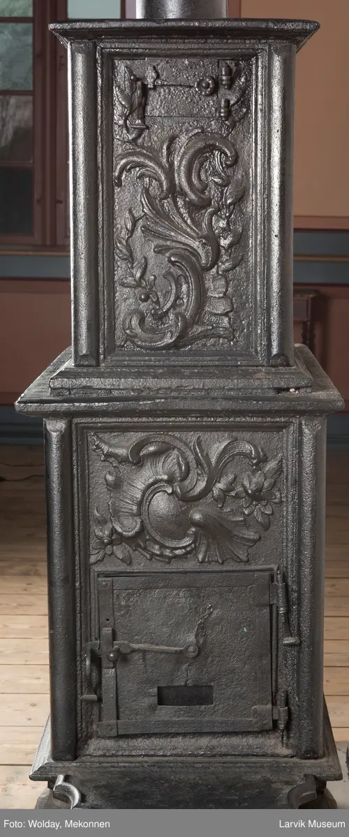 Ovn i  2 etasjer. 
Rokokko, jfr. nr 411 i Norsk Jernskulptur b II 
1. etasje langside: Mars sitter på en kanon med sverd i høyre hånd. Riflet bunn.
1 etasje kortside: Øverst: Rokokko-ornament, nederst: Grevekrone monogram. FL og 1756 
nederst: ovnsdør 2 hengsler ovalt askebrett med profilert kant.
2.etasje langside: Fyldig rokokko-ornament. med blomster. Uregelemessig portalåpning. 
2. etasje kortside: Rokokko-ornament, 
Ovnen har sungne ben m/dyreføtter