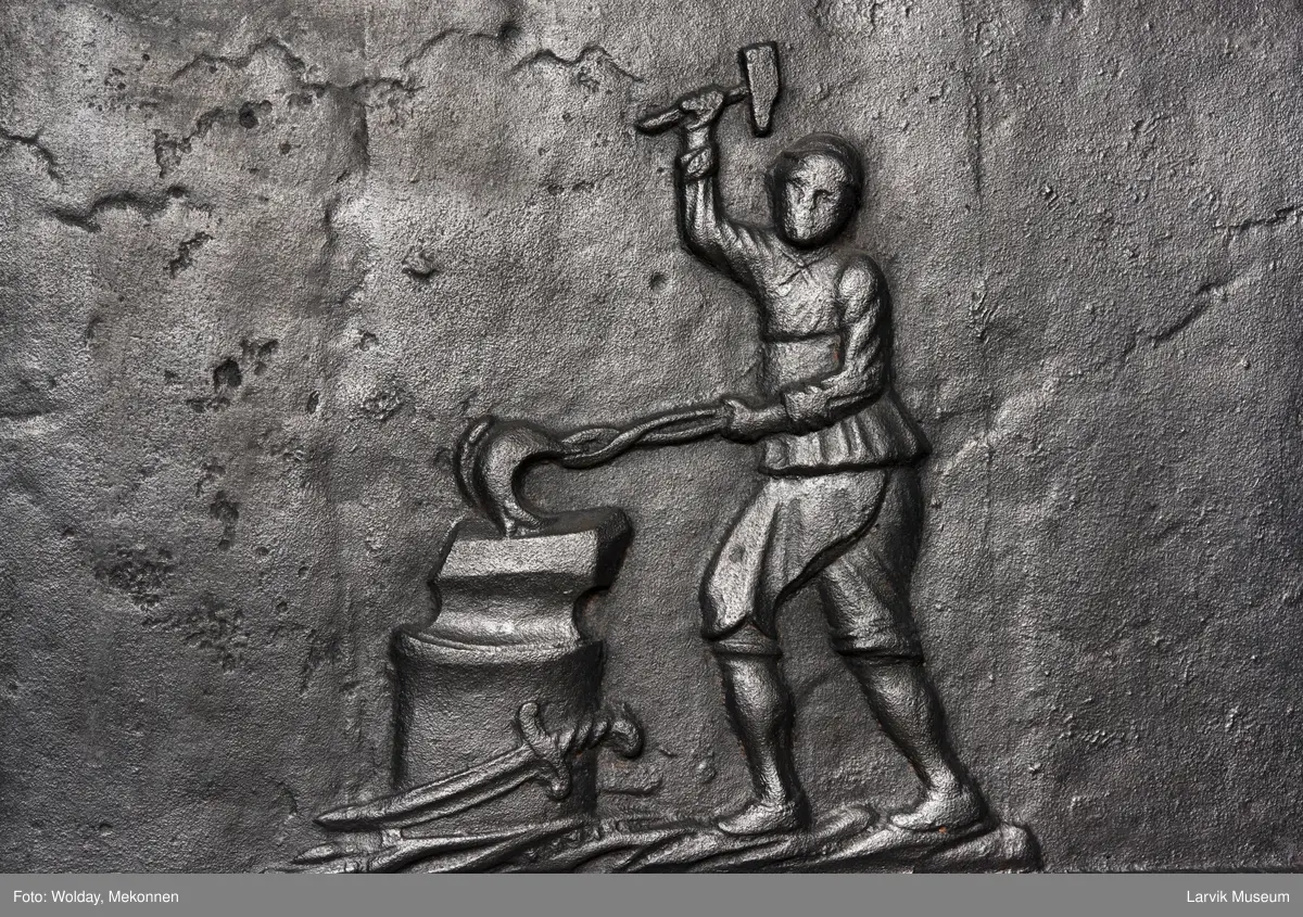 Jernovn med to etasjer, begge er rektangulære. Ovn står på muret fot/understell.
1etasje langside: Vulkan som smed .
1etasje kortside: Musling. 
2etasje langside: Buet åpning i profilert innramming omgitt av girlander. 
2etasje kortside: Overflødighetshorn.