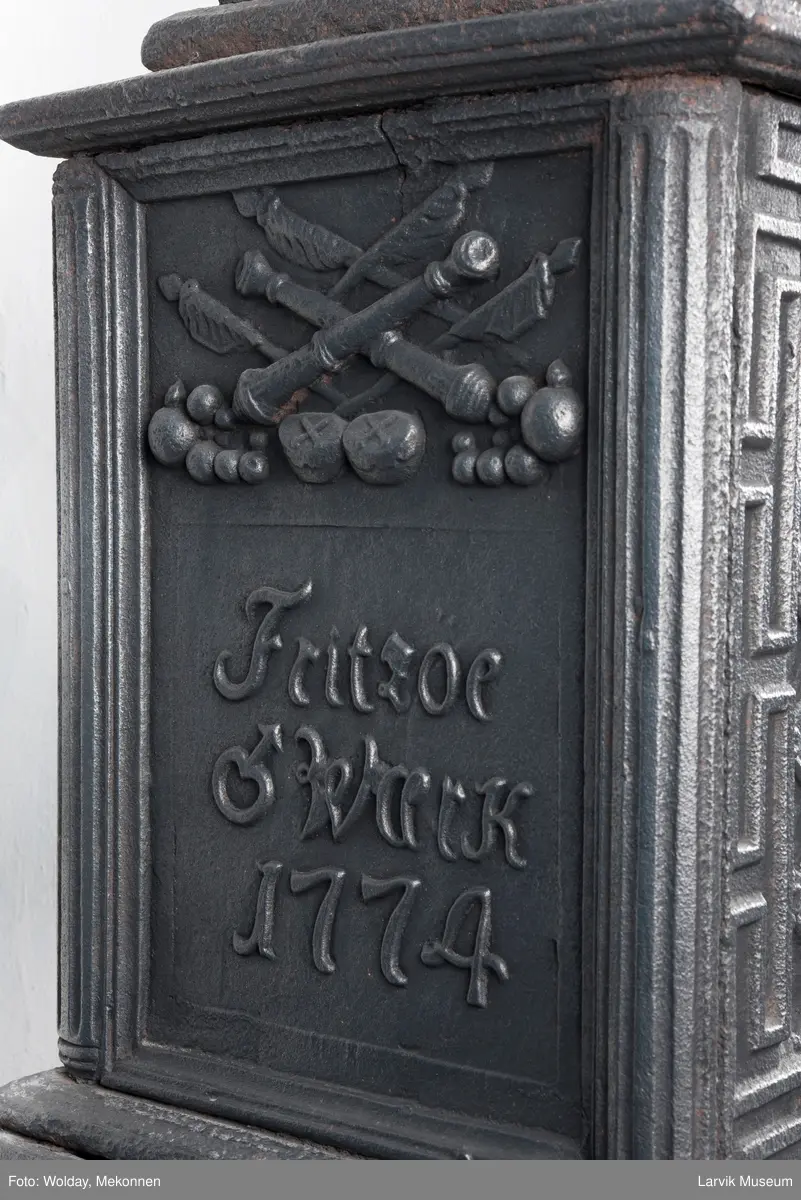 1. etasje langside: Chr. VII's byste, rosetter, meander ramme.
1. etasje kortside: Krigerske emblemer over Fritzøe Wærk 1774, under krigerske emblemer, dør med gjennombrudd blomstermønster
2. etasje langside: Rundbuet åpning med kanellert ramme, øverst kroningsregaliene, gitret bunn.
2.etasje kortside: kronet C7 på gitret bunn jfr. nr 420 i Norsk Jernskulptur II.