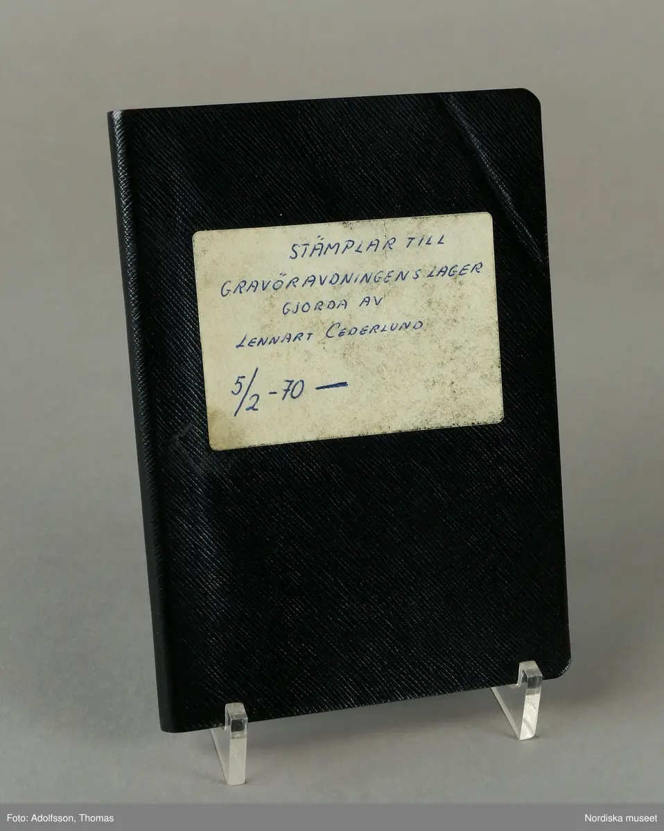 Arbetsbok, gravörjournal. Svart vaxdukshäfte, inlaga av randigt papper. Text på etikett på framsidan"STÄMPLAR TILL GRAVÖRAVDELNINGENS LAGER GJORDA AV LENNART CEDERLUND 5/2 -70 -". Tryckt text på insidan av pärmen 415.67 Tillhör Statsveket".

Handskriven journal förd 1970-1980 över vid Kgl. Mynt- och Justeringsverket av gravören Lennart Cederlund.tillverkade guldsmedsstampar och årsbokstäver.
/2007-03-05 Heidi Henriksson