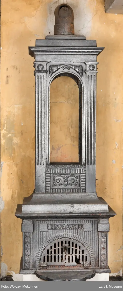 Ovn med avtrappet topp, ovalt, bølget askebrett. 
1. etasje langside: halvsirkelformet. Døren er hengslet i underkant. Over denne på plate står det Fritzøe Wærk. Riflet bunn, lisener med bladverk ved hjørnene. 1. etsje kortside: Rosett, riflet bunn, 
2. etasje langside: Rundbuet åpning, lister til 4 etasjeplater. Over åpning 2 overflødighetshorn, under palmett i riflet ramme. kannelserte pilastre i hjørnene. 2. etasjekortside: Rosett på riflet bunn, bølgemeander.