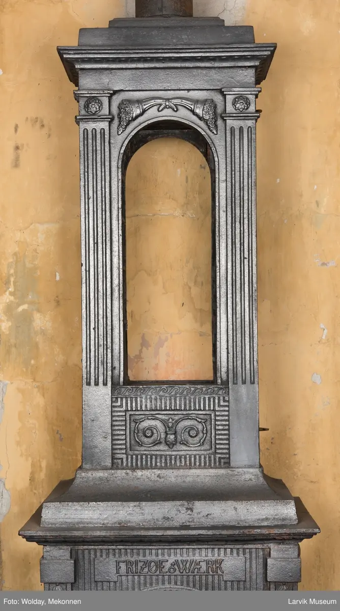 Ovn med avtrappet topp, ovalt, bølget askebrett. 
1. etasje langside: halvsirkelformet. Døren er hengslet i underkant. Over denne på plate står det Fritzøe Wærk. Riflet bunn, lisener med bladverk ved hjørnene. 1. etsje kortside: Rosett, riflet bunn, 
2. etasje langside: Rundbuet åpning, lister til 4 etasjeplater. Over åpning 2 overflødighetshorn, under palmett i riflet ramme. kannelserte pilastre i hjørnene. 2. etasjekortside: Rosett på riflet bunn, bølgemeander.