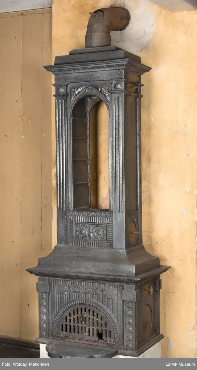 Ovn med avtrappet topp, ovalt, bølget askebrett. 
1. etasje langside: halvsirkelformet. Døren er hengslet i underkant. Over denne på plate står det Fritzøe Wærk. Riflet bunn, lisener med bladverk ved hjørnene. 1. etsje kortside: Rosett, riflet bunn, 
2. etasje langside: Rundbuet åpning, lister til 4 etasjeplater. Over åpning 2 overflødighetshorn, under palmett i riflet ramme. kannelserte pilastre i hjørnene. 2. etasjekortside: Rosett på riflet bunn, bølgemeander.