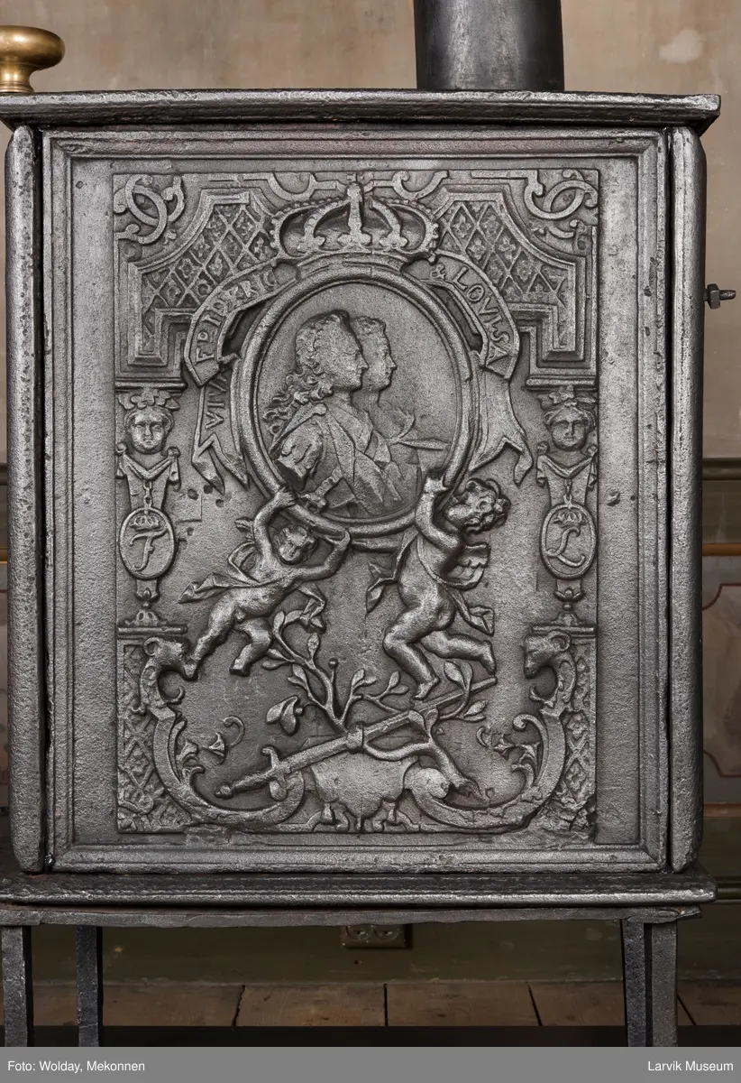 Ovnen har understell, bunnplate, sideplater, frontplate, bakplate og topp, røykkasse, røykerør og to messinghoder. Røykerøret er litt løst.