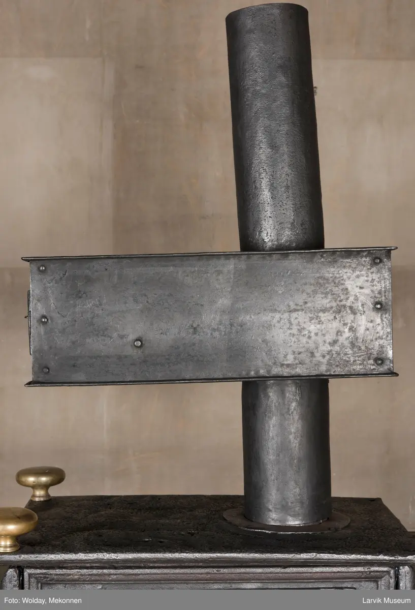 Ovnen har understell, bunnplate, sideplater, frontplate, bakplate og topp, røykkasse, røykerør og to messinghoder. Røykerøret er litt løst.