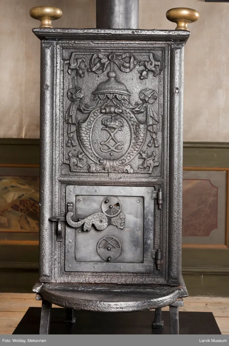 Ovnen har understell, bunnplate, sideplater, frontplate, bakplate og topp, røykkasse, røykerør og to messinghoder. Røykerøret er litt løst.