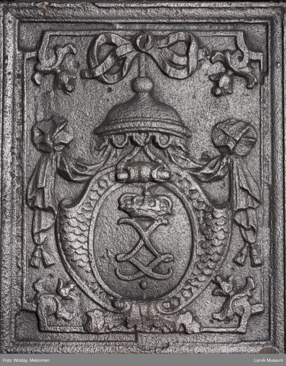 Ovnen har understell, bunnplate, sideplater, frontplate, bakplate og topp, røykkasse, røykerør og to messinghoder. Røykerøret er litt løst.