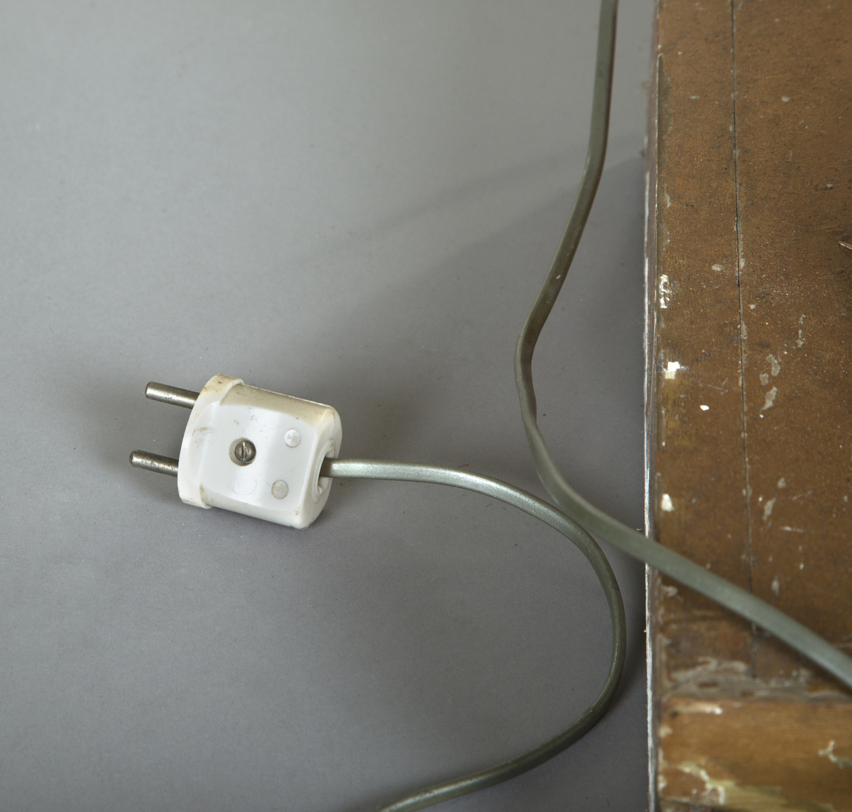 Forgylte gulvstående lamper for flere lys, både stearinlys og elektrisk. Hull til stearinlys langs kanten på hele topp-platen. En åpen lampeskjerm i glass omkranser det elektriske lyset midt på abakus, med bølgende kant (som en fakkel). Lampen er formet som en frittstående gresk søyle med base. Glatt utforming, med et område med bladutskjæringer like under midten, samt på kapitélet. Rund abakus og firkantet base.