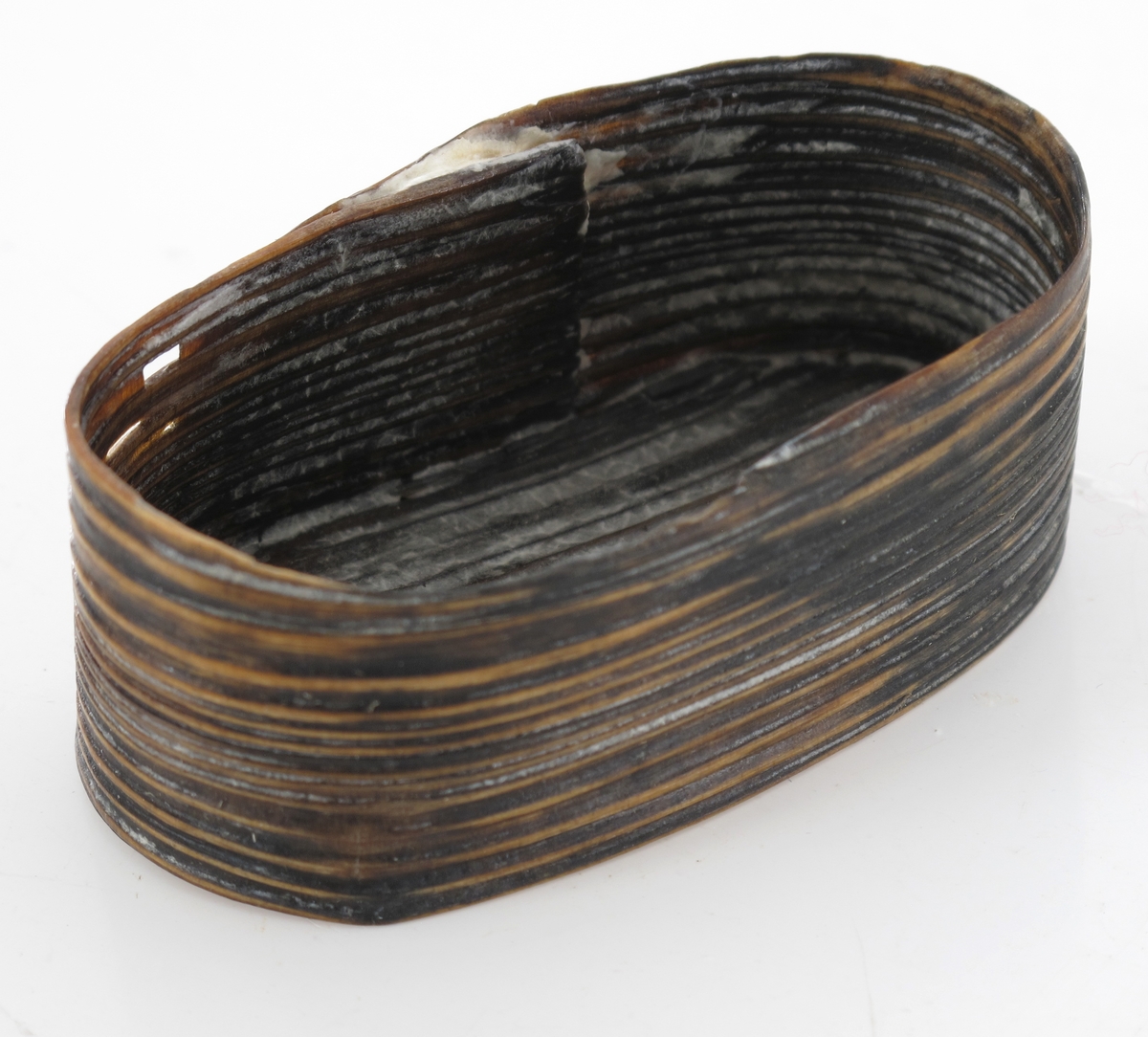 Liten oval eske (ask), Sveipet av tre. Oval bunn, rettsidet eske, lokk mangler.  Lå inni den større ovale esken med  myntene, knapper, de to signeter m. m.