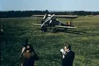 Klargöring av flygplan FVM Tummeliten märkt nummer 3656 vid flygdagarna på Malmen 1-2 september 1962, vid firande av militärflyget 50 år. I förgrunden står en man vid en filmkamera samt en speaker med megafon.