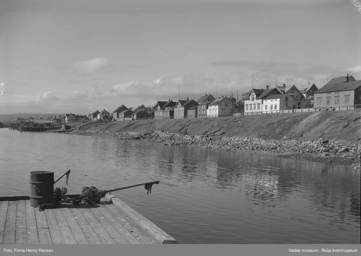 Vadsø sentrum mot indrebyen og Havnegata. Bildet er tatt mot vest. I forgrunnen ser vi en del av Samvirkekaia. De fleste av førkrigshusene står der fortsatt. Bildet er tatt en sommerdag og sannsynligvis på 50-tallet.