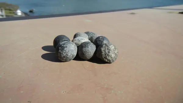 Ni kuler på en overflate, i bakgrunnen utsikt over ei bukt.