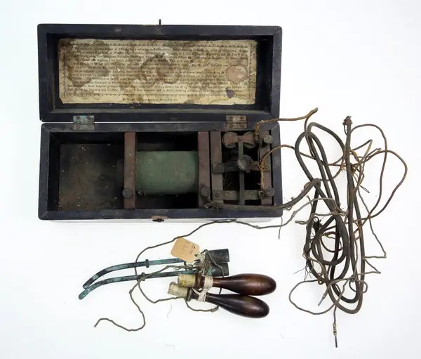 Apparat i trekasse med lokk hengslet på langsida. Inne i lokket er det trykt bruksanvisning. Brukt mot sykdom.