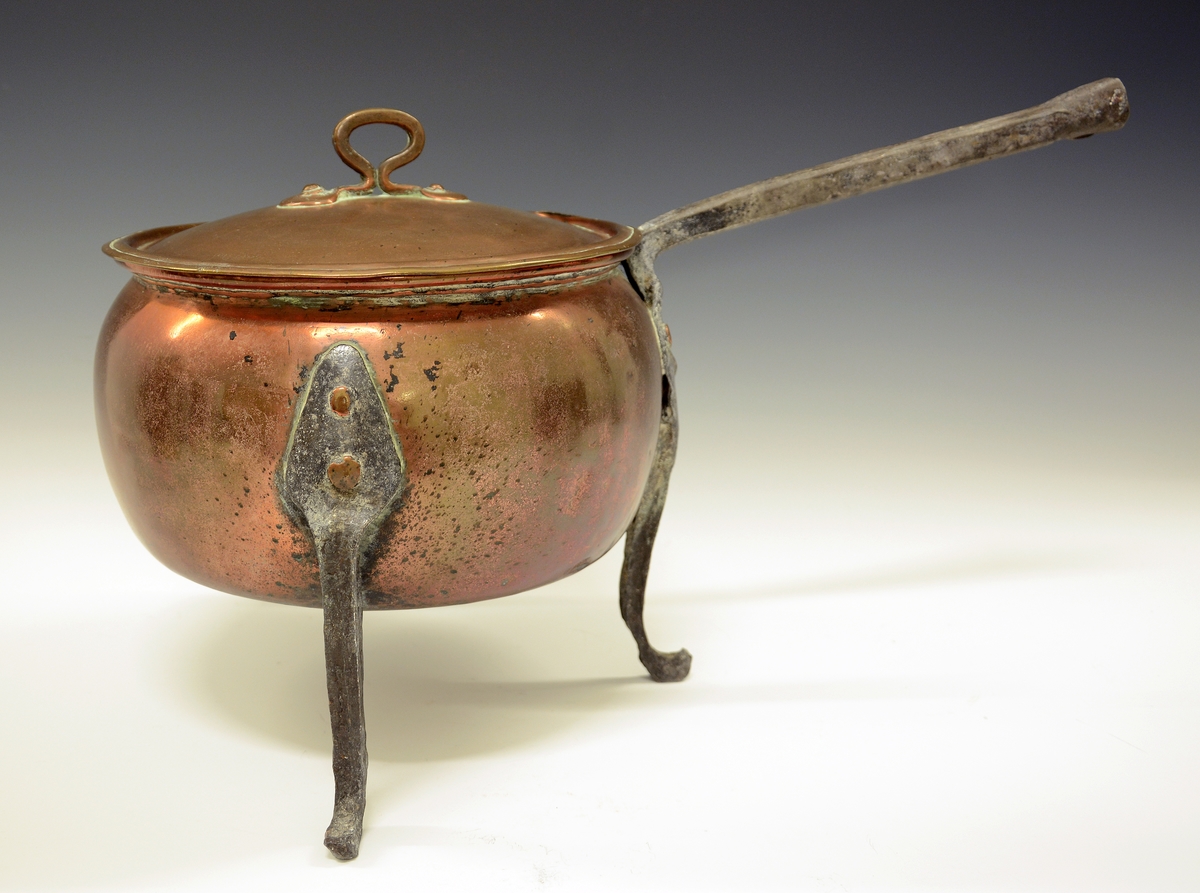 Gryte av kobber. Tre høye jernføtter og jernhåndtak, lokk med håndtak.