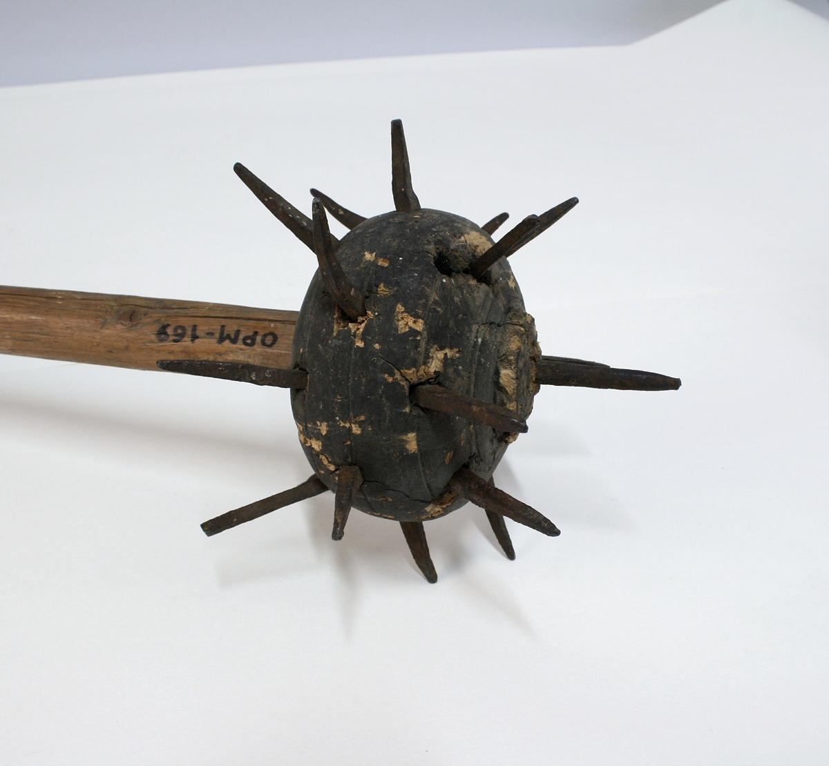 Trestav med en piggete blykule øverst. Kulen har 19 pigger. Staven har en doppsko av jern nederst, formet som en holk med en jernpigg.