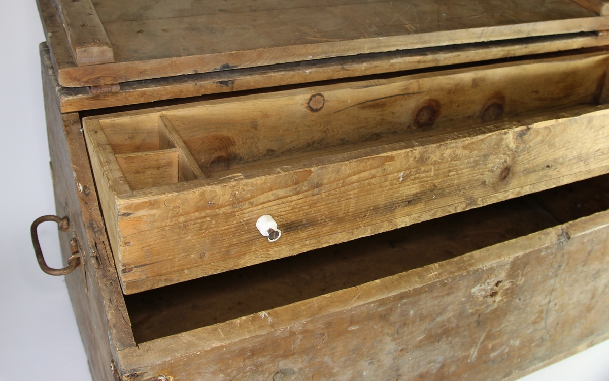 Verktøykiste av tre. Skråstilt lokk. Skuff øverst i rommet. Handtak på sidene.