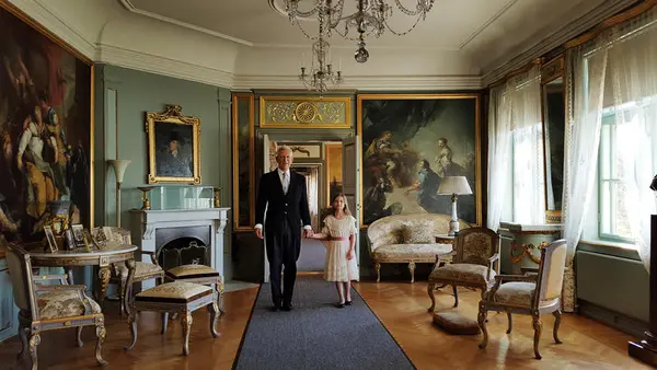 En bestefar og en jente i penklær i hovedbygningen på Bogstad gård. 