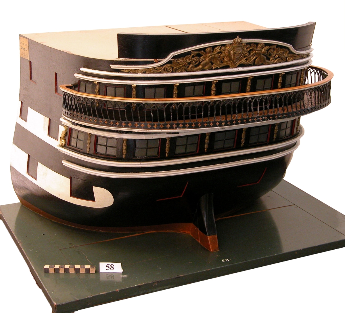 Fartygsmodell akterstäven av ett linjeskepp från mitten av 1800-talet. Blockmodell utan några tillbehör, svartmålad och 2 vita ränder åt sidorna längs batterierna. Akterskeppet försett med förgyllda ornament och galleri.