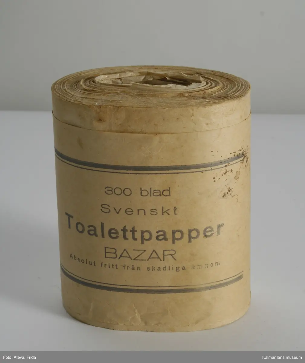 KLM 44780. Toalettpapper, av papper. En rulle toalettpapper. På omslagspappret texten: 300 blad Svenskt Toalettpapper Bazar Absolut fritt från skadliga ämnen.