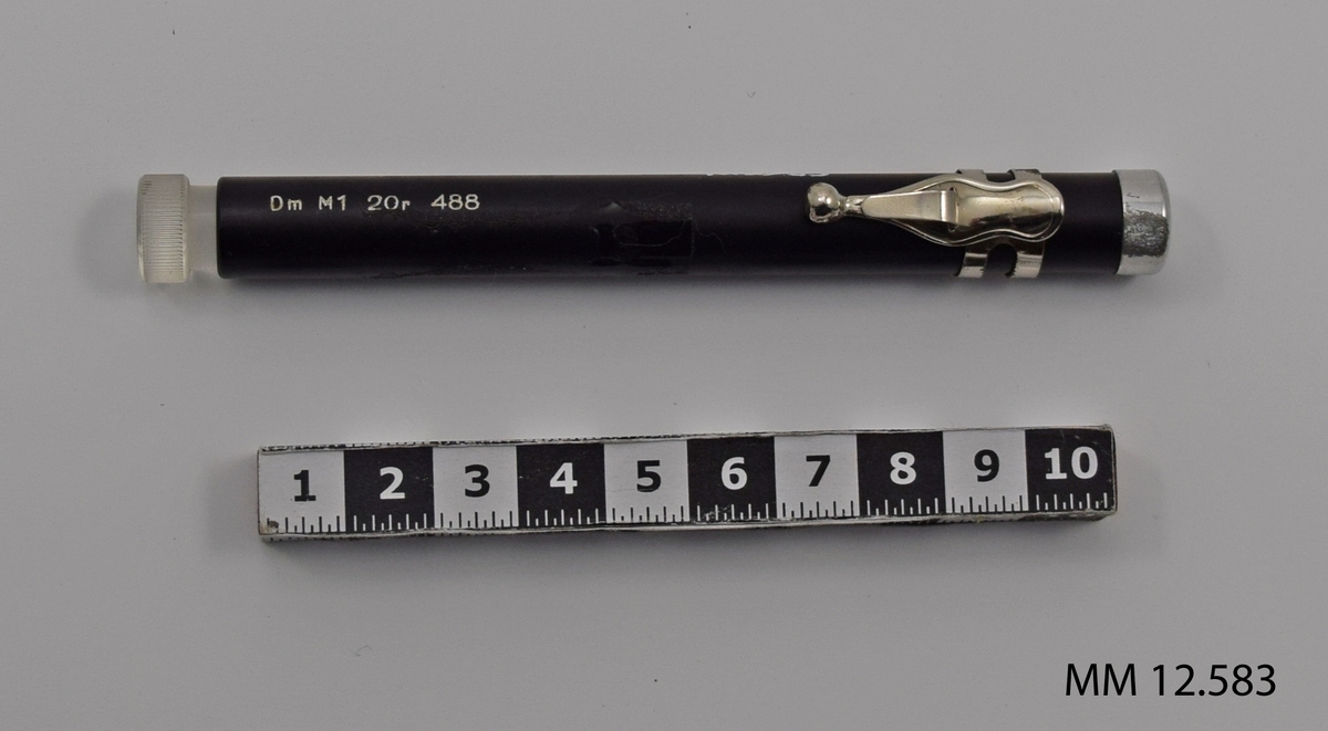 Rörformad dosimeter av plast. Försedd med klämma. Avsedd att bäras i fickan.