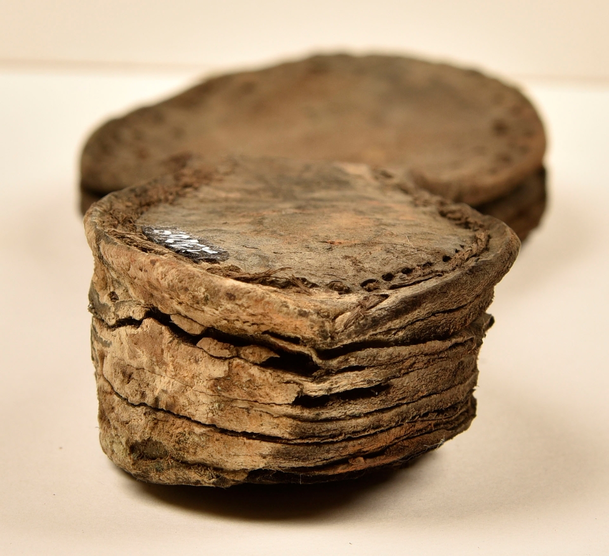 Dokumentation 1996:
Delar och fragment av sko: en skobotten samt ett fragmentariskt ovanläder, tre bitar av ett filtliknande material, ett 15-tal fragment av bottenläder samt sex mindre fragment av trä.
Skobottnen har kvarsittande tråd och träpligg. Yttersulan är ritsad. Klacken består av fem klacklappar som är placerade mellan ytter- och innersulan. Innersulans läder är mycket kraftigt, ca 6 mm tjock. Ovanlädret är sprött och fragmentariskt samt har blå och rostfärgade utfällningar.

Text in English: 
Various parts and fragments of a shoe, consisting of a sole with fragments of vamp (upper leather), three pieces of a felt-like material, some 15 fragments of sole or bottom leather and six smaller fragments of wood.
There are remains of thread and wooden pegs on the shoe sole. The outsole is channeled. The heel is made up of five heel lifts placed between the insole and outsole. The leather of the insole is very thick, ca 6 mm. The upper leather is fragile and fragmentary, and has blue and rust-coloured precipitations.

Dokumentation 2022:
Skobotten och delar av ovanläder till en öppen randsko. Tillverkade i getskinn av god kvalitet. Skapades på en rak läst och bars på höger fot. Klacken som är lagad med en läderlapp under sulan. Inga dekorationer. Det finns tecken på delaminering. Fragment från en stickad strumpa hittades inuti skon. Det finns lagningar med träpligg på sulan och hälen. Skobotten hör ihop med fyndnummer 23070.
För mer information, se Länkade filer: Uppritning

Text in english:
This is the bottom unit and upper fragments of an open shoe, made of goatskin leather of good quality, of randed construction with a patch heel, made on a straight last and worn on the right foot, with no decorative features. The bottom unit pairs with 23070. There are signs of delamination and fragments of a knitted stocking were found inside the shoe. There are pegged repairs to sole and heel.
For more information, go to Länkade filer: Uppritning