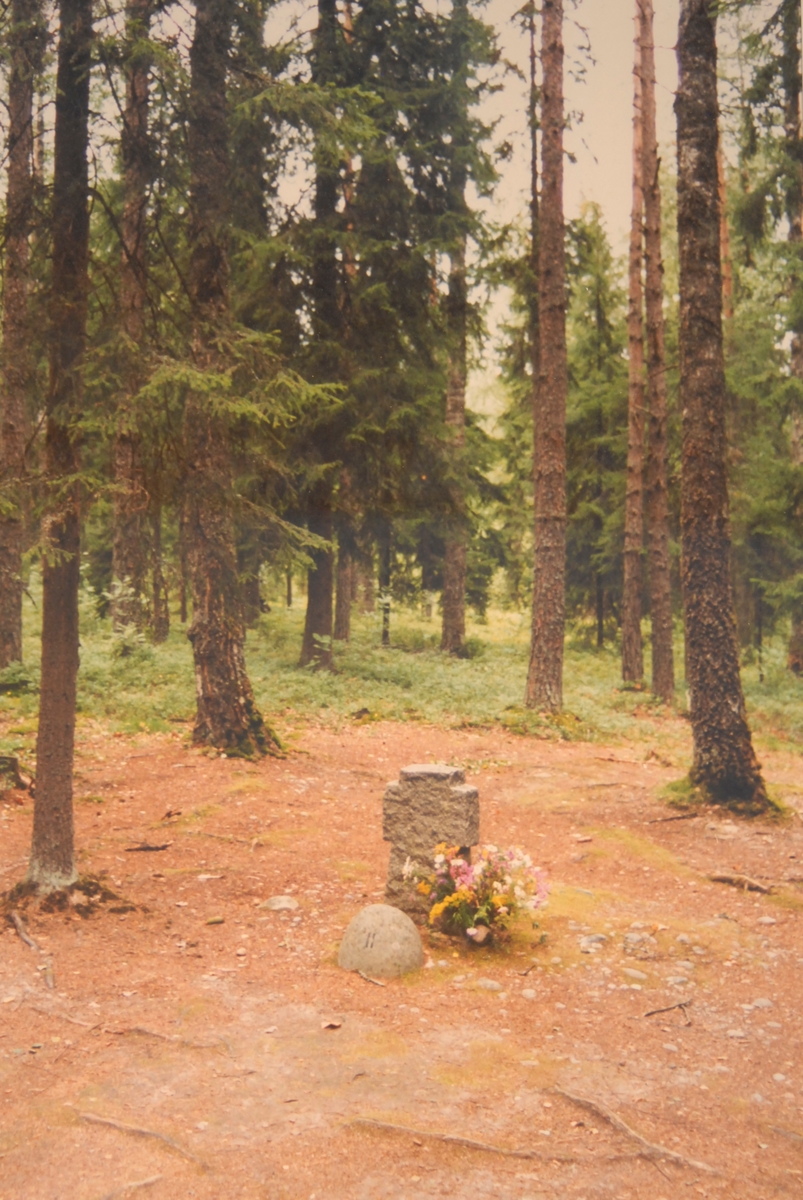 Rettersted i Trandumskogen. Gravstein med blomar.