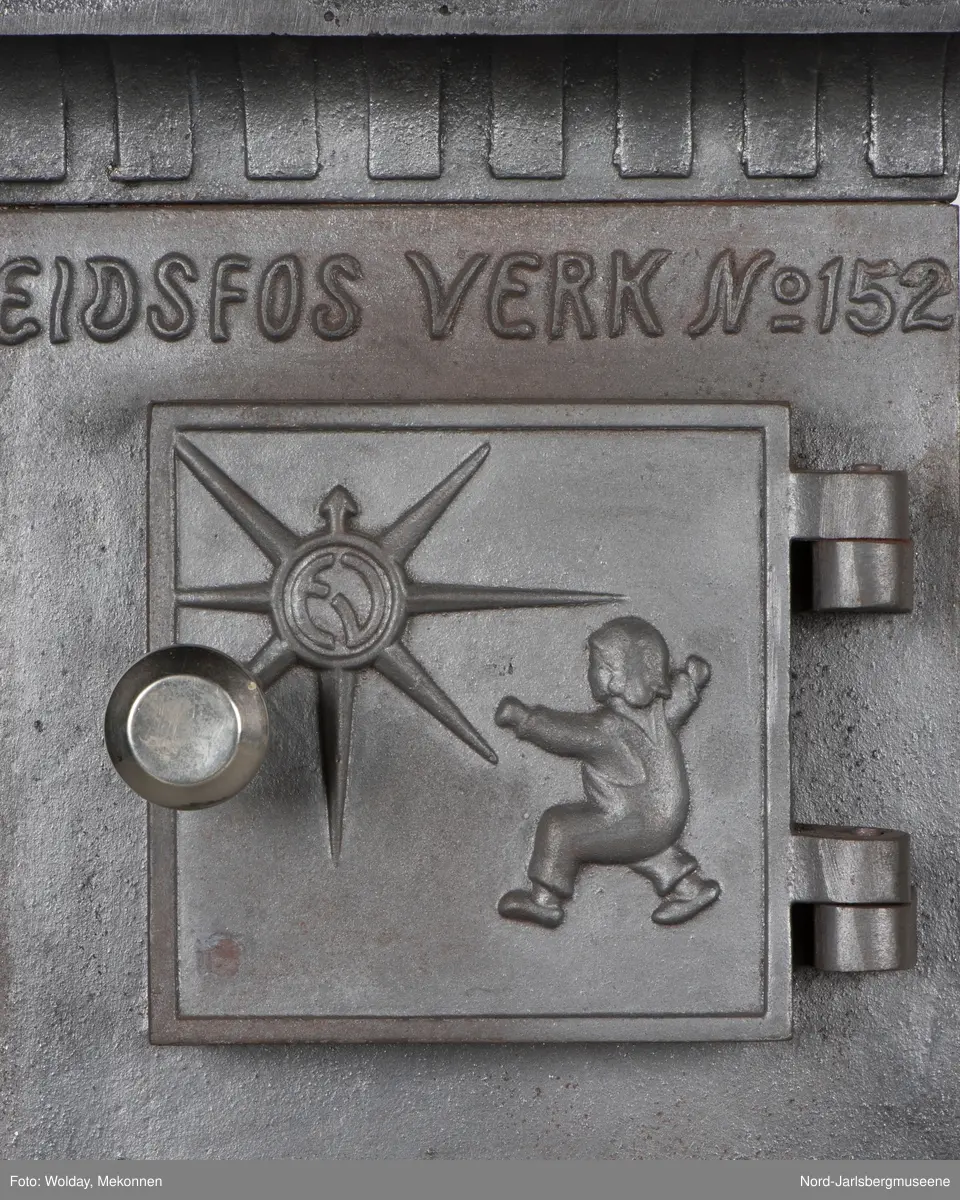 Dekor:   "Smørbukk" på dør til askeskuff/ildkammer, "kjerringa med staven" på ovnen, gutt og sol på koksdør, klassisk tannfrise under topplokk.