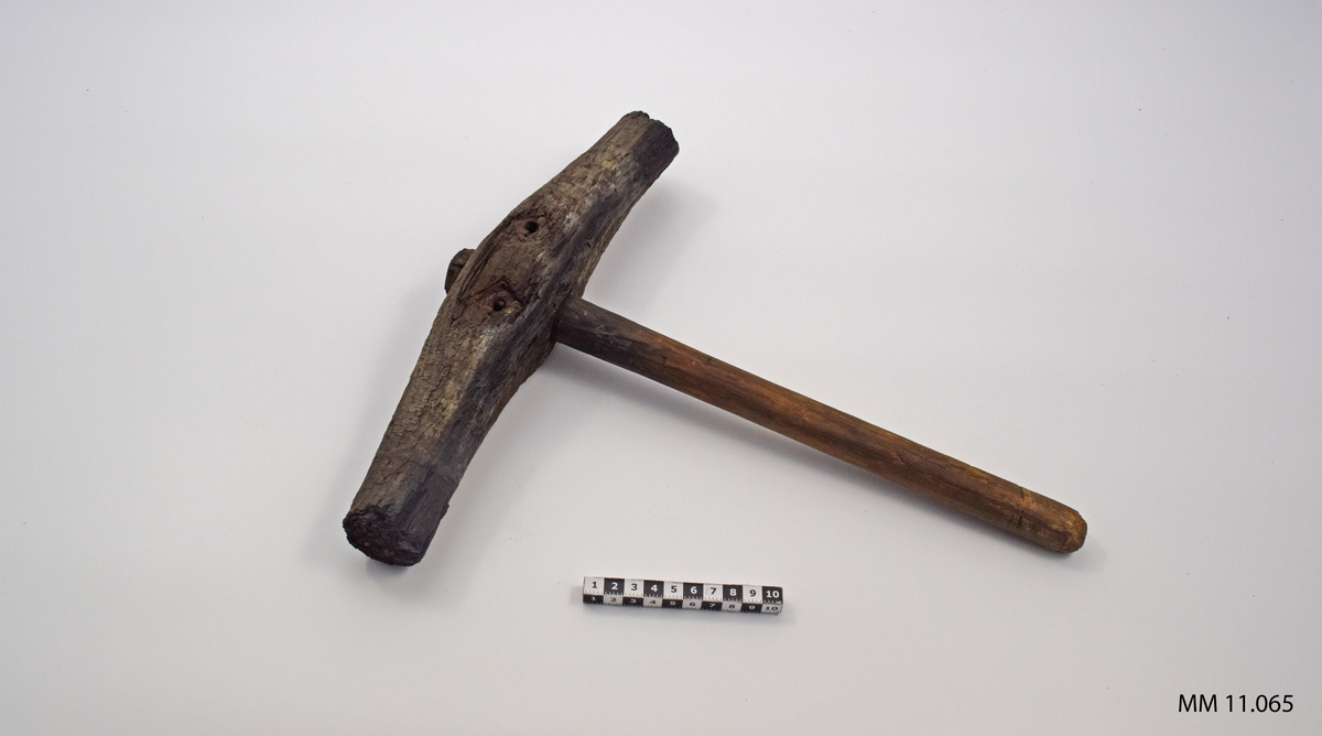 Drevhammare av trä. Hammaren tillverkad under år 1708. Bågformad, på mitten försedd med genomgående runt träskaft. Nitar vid skaft och ringar kring slagen saknas (är sönderrostade).