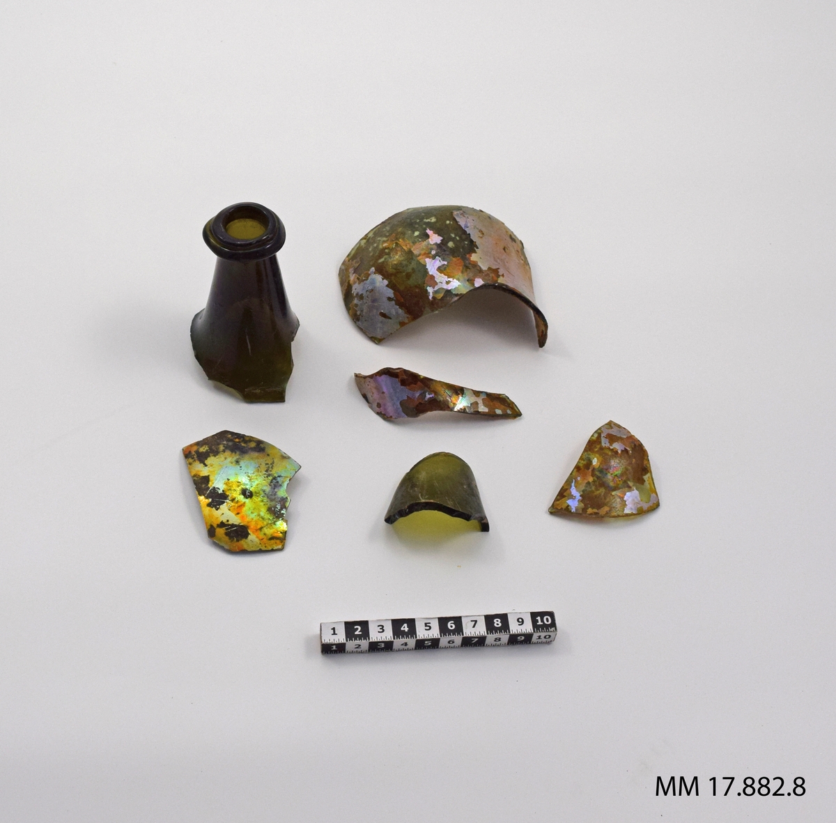 Sjöfynd från vraket Nya Riga. Glas, femton stycken mindre fragment, iriserande, ett större samt en flaskhals.

För dimensioner på den enskilda bitarna, se inventariebilaga.