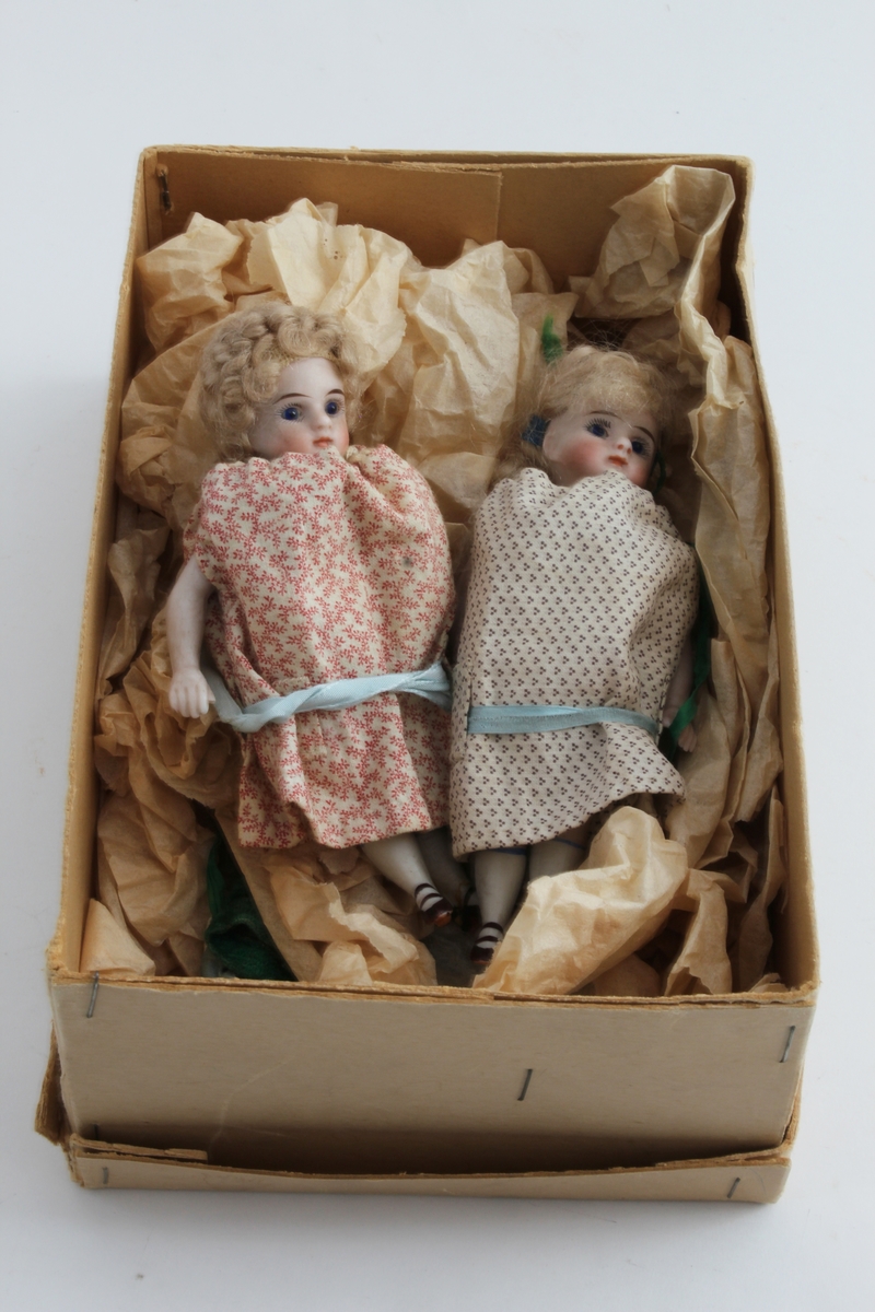 Ganske sikker giver: Karen Collett (f.1921)
To stykk små porselensdukker. Ene med kort krøllete hår, rød blomstrerte kjole med blått silkebånd og påmalt ansikt og sko. Den andre med langt lyst hår i brunprikkete kjole med blått silkebånd og påmalt ansikt og sko.